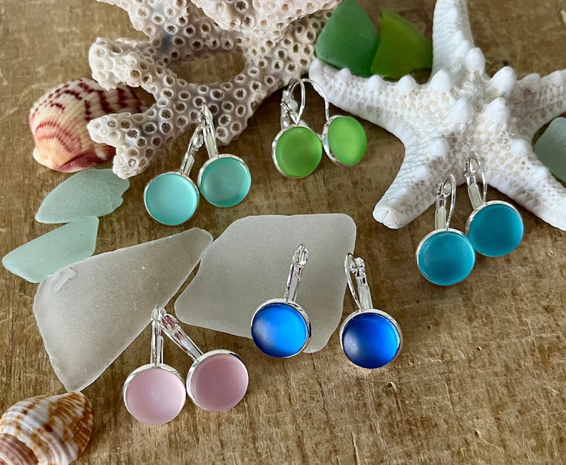 May include: Assortment of sea glass earrings in various colours, including pink, blue, and green. The earrings are made with silver-toned leverback fastenings.