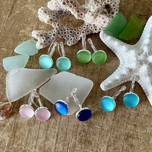 May include: Assortment of colourful glass earrings in shades of blue, green, and pink. The earrings are made of glass and have a silver tone metal setting.