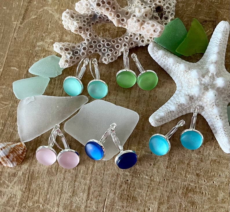 May include: Assortment of colourful glass earrings in shades of blue, green, and pink. The earrings are made of glass and have a silver tone metal setting.