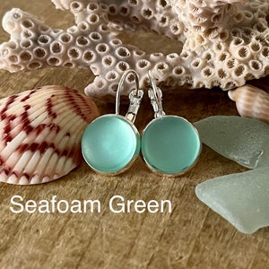 May include: Seafoam green glass earrings with silver hooks. The earrings are round and have a frosted finish.