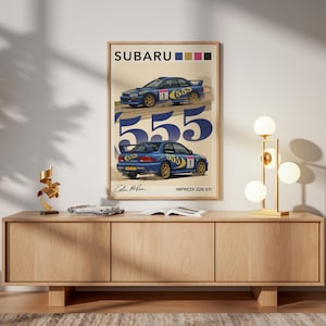 May include: A framed poster featuring two blue Subaru Impreza 22B STI rally cars with the number 555. The poster has the Subaru logo at the top and the text "Colin McRae" and "Impreza 22B STI" at the bottom.