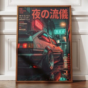 May include: A framed poster featuring a silver hatchback car parked on a wet city street at night. The scene is illuminated by red and teal neon signs. Japanese text is visible throughout the poster, including the large title 夜の流儀.