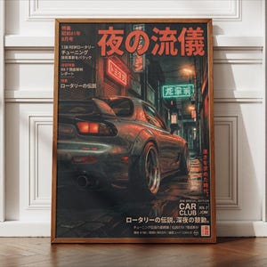Peut inclure: Une affiche encadrée représentant une voiture de sport gris foncé garée dans une rue urbaine humide la nuit. L'illustration comprend du texte japonais, des enseignes au néon et les mots CAR CLUB RX-7 JDM. La scène est éclairée par des reflets rouges et verts.