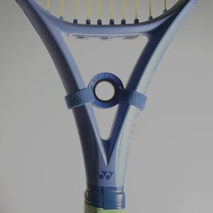 Puede incluir: Una raqueta de tenis azul con cuerdas amarillas y un agarre verde. La raqueta tiene una banda azul con el texto "TOP SPINNE" alrededor del centro. El logotipo de Yonex es visible en el mango.