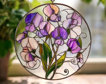 May include: Round stained glass window art featuring a floral design with purple, lavender, and white flowers. The glass is framed with a dark metal border and includes green leaves. The artwork is designed to hang and is suspended by a chain.