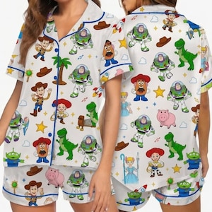 May include: A white short-sleeve button-down pajama shirt and matching shorts set featuring a repeating pattern of Toy Story characters including Woody, Buzz Lightyear, Jessie, Rex, Mr. Potato Head, Slinky Dog, Hamm, and the green aliens with yellow stars.
