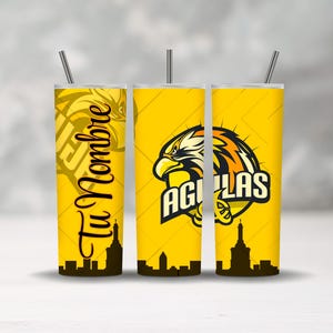 May include: Three yellow insulated tumblers with silver straws. The tumblers feature a black skyline design at the base. One tumbler has the text "Tu Nombre" in black script. The other two tumblers have an eagle logo and the word "AGUILAS".