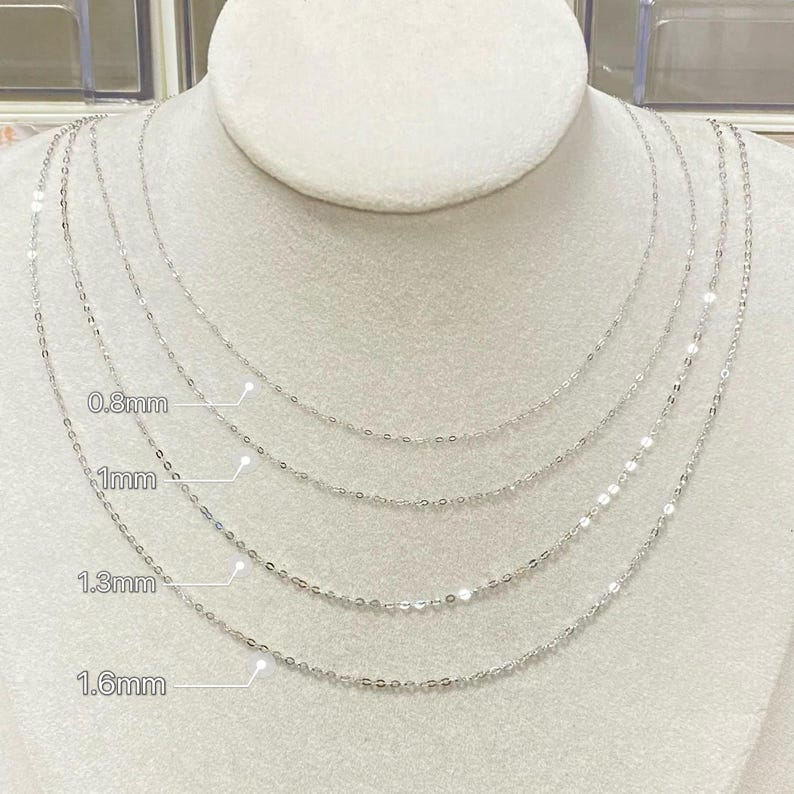 Peut inclure: Quatre colliers argent&eacute;s d&eacute;licats de diff&eacute;rentes &eacute;paisseurs sont pr&eacute;sent&eacute;s sur un buste de mannequin blanc. Les colliers sont &eacute;tiquet&eacute;s avec leurs largeurs : 0,8 mm, 1 mm, 1,3 mm et 1,6 mm. Les cha&icirc;nes sont fines et semblent &ecirc;tre en m&eacute;tal brillant.