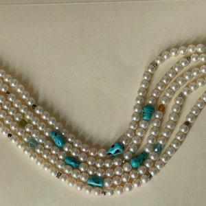 May include: A multi-strand pearl necklace with turquoise and green accents. The necklace has a silver clasp.