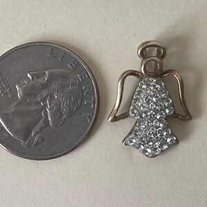 May include: A silver angel charm with clear rhinestones. The charm is about the size of a 20 pence coin.