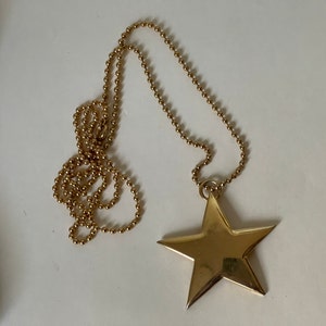 May include: A gold chain necklace with a large gold star pendant.