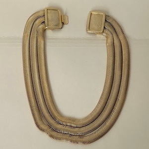 May include: A gold-tone multi-strand necklace with a woven chain design. The necklace has a clasp closure.