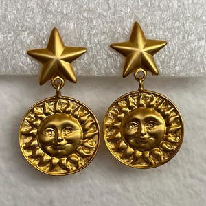 May include: A white ceramic mug with a black handle and the text "But First, Coffee" in a bold, black font. The mug is set against a blurred background, suggesting a cozy setting.