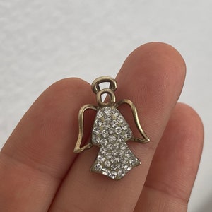 May include: A silver angel charm with a halo and wings, adorned with clear rhinestones.