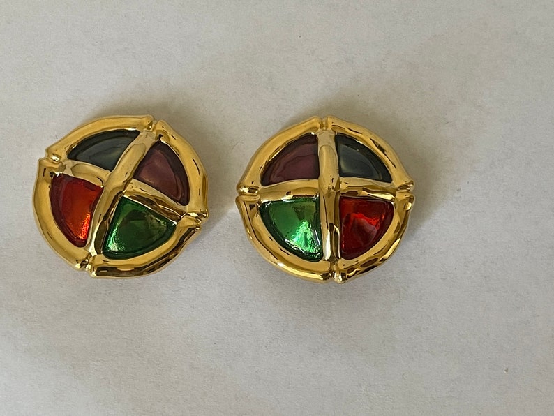 May include: A pair of gold tone earrings with a circular design. Each earring features four colored glass stones in a cross pattern.