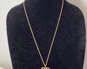 May include: A gold chain necklace with a heart-shaped pendant featuring a small dog figurine inside.