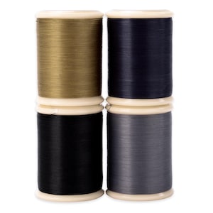 May include: Four spools of thread in various colors: gold, navy blue, black, and gray. Each spool is wound around a white plastic core with a matching top and bottom. The threads appear smooth and tightly wound, suitable for sewing or crafting projects.