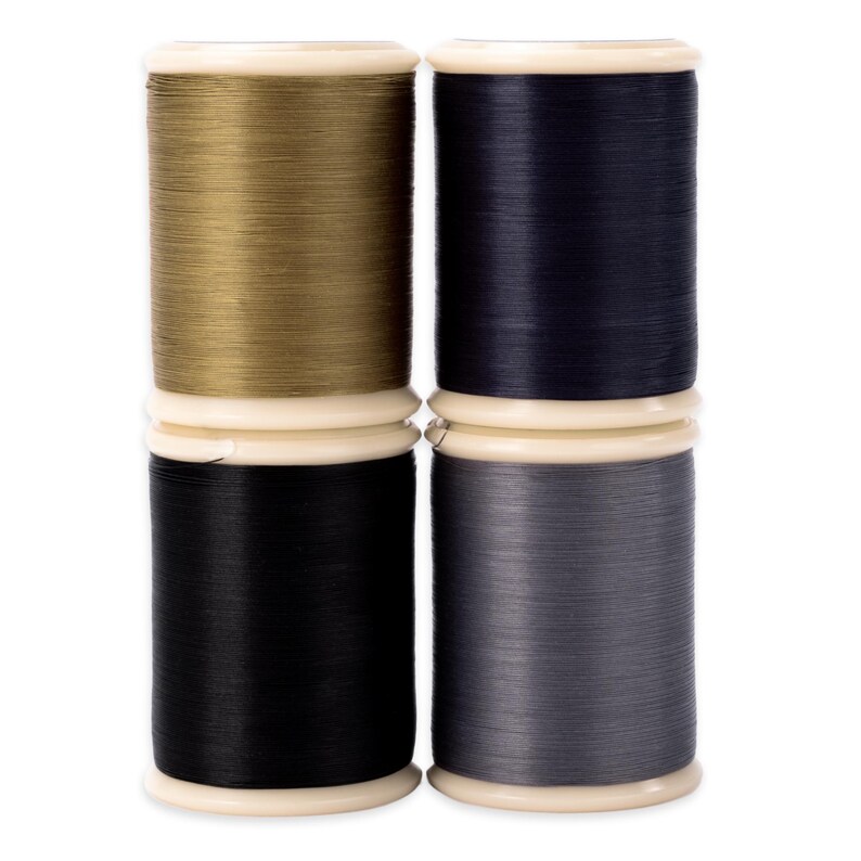 May include: Four spools of thread in various colors: gold, navy blue, black, and gray. Each spool is wound around a white plastic core with a matching top and bottom. The threads appear smooth and tightly wound, suitable for sewing or crafting projects.