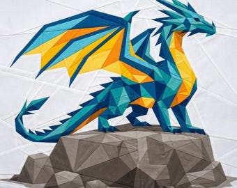May include: A geometric fabric quilt block featuring a dragon with teal, blue, and yellow wings and body, standing on a gray rock formation. The design is composed of angular, pieced fabric segments against a white background.