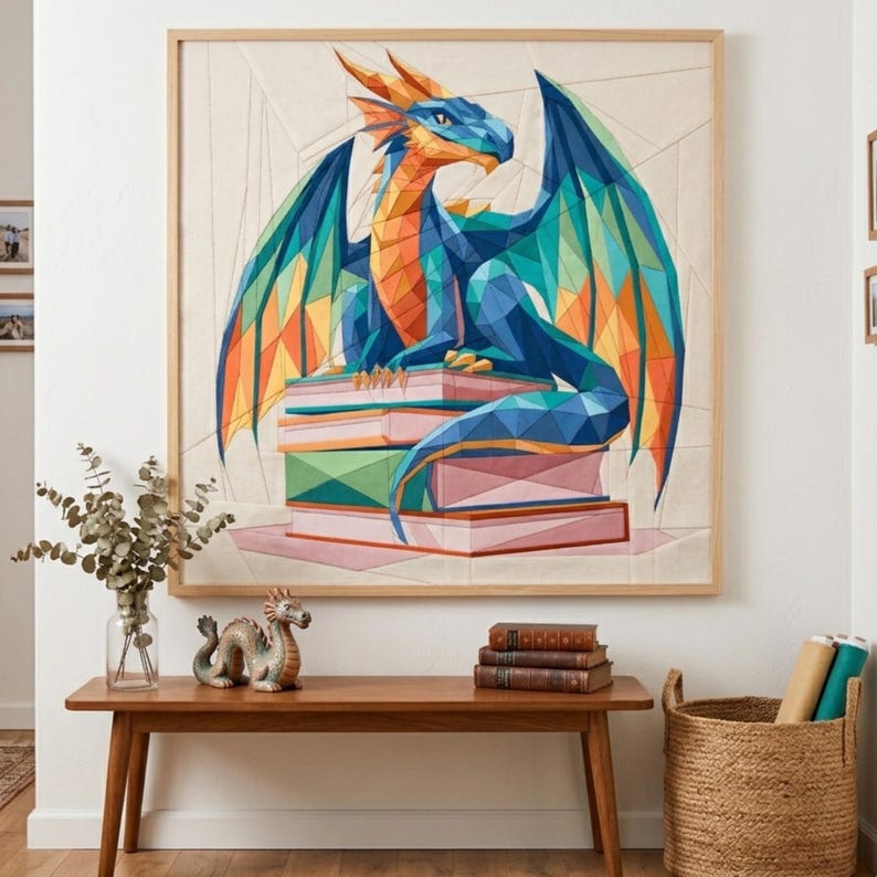 May include: A square wall art piece in a light wood frame featuring a geometric, low-poly style illustration of a dragon with blue, orange, and green scales perched atop a stack of books, set against a cream-colored background with subtle lines.