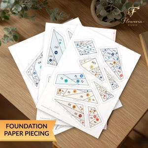 May include: A stack of white paper sheets featuring foundation paper piecing templates with geometric shapes, dashed cut lines, and numbered sections in shades of blue, orange, and beige, labeled with codes like CS7, T3, and Q1 for quilting projects.