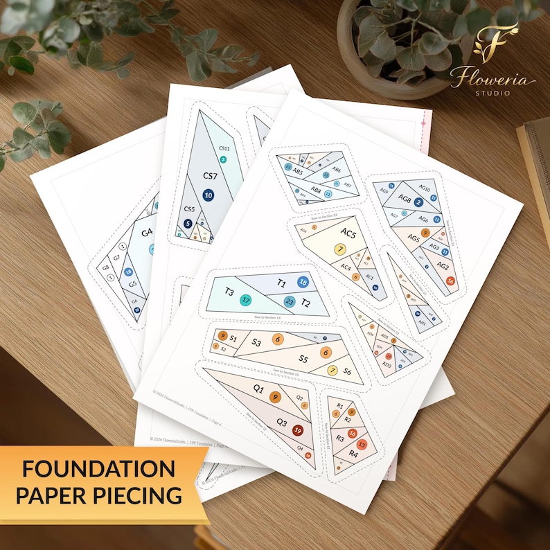 May include: A stack of white paper sheets featuring foundation paper piecing templates with geometric shapes, dashed cut lines, and numbered sections in shades of blue, orange, and beige, labeled with codes like CS7, T3, and Q1 for quilting projects.