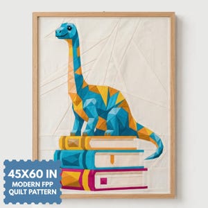 May include: A quilt pattern featuring a geometric, low-poly style dinosaur in shades of blue and yellow, perched atop a stack of three books. The design is set against a cream background within a light wood frame, labeled 45X60 IN MODERN FPP QUILT PATTERN.