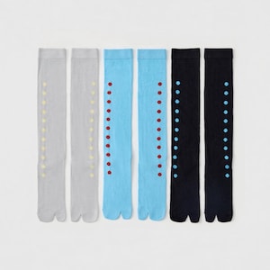 May include: Three pairs of split-toe tabi socks in light gray, light blue, and black. Each pair features a vertical row of small circular dots along the side. The light gray socks have yellow dots, the light blue have red dots, and the black have blue dots.