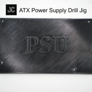 May include: A black ATX Power Supply Drill Jig with the letters "PSU" embossed on the front. The jig has four holes in the corners and the text "ATX Power Supply Drill Jig" is printed above the jig.