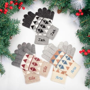 Può includere: Tre paia di guanti invernali personalizzati con motivi geometrici e nomi ricamati sui polsini. I guanti presentano schemi di colori grigio, crema e marrone, con nomi come "Jack", "Ella" e "Aria".