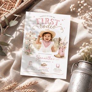 May include: A rectangular birthday invitation card featuring a photo of a child in a cowboy hat and bandana. The text reads Saddle Up For My First Rodeo, Samantha's 1st Birthday, and includes event details, a wooden sign graphic, and a pink cowboy boot.