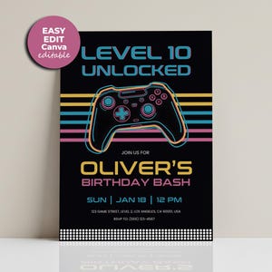 Può includere: Biglietto d'invito nero con grafica di un controller di videogiochi e la scritta "LEVEL 10 UNLOCKED". L'invito include anche la scritta "OLIVER'S BIRTHDAY BASH" e i dettagli dell'evento.