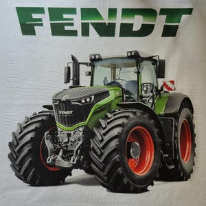 Könnte beinhalten: Ein weißes T-Shirt mit einer großen Grafik eines grünen Fendt-Traktors mit schwarzen Reifen und roten Felgen. Das Wort FENDT ist in großen grünen Buchstaben über dem Traktor gedruckt. Der Text @HolzenForst Technik steht in Weiß am unteren Rand.