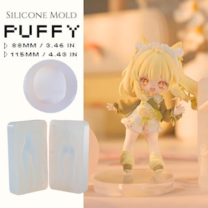 Peut inclure: Un ensemble de moules en silicone pour le bricolage, avec le mot "PUFFY" et des mesures de 88 mm et 115 mm. L'ensemble comprend un moule rond et deux moules rectangulaires. Une petite figurine de personnage de dessin animé est également présente.