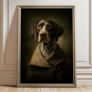 Könnte beinhalten: Ein gerahmtes Porträt eines braun-weißen Deutsch Kurzhaar Hundes, der einen dunkelbraunen Mantel mit Kragen trägt. Der Hund hat eine gesprenkelte Brust und blickt vor sich hin vor einem dunklen, stimmungsvollen Hintergrund. Der Rahmen ist metallisch.