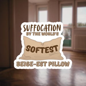 May include: A sticker with a beige pillow illustration and text. The text reads "SUFFOCATION BY THE WORLD'S SOFTEST BEIGE-EST PILLOW" in brown font. The sticker has a white border and is set against a blurred room background.