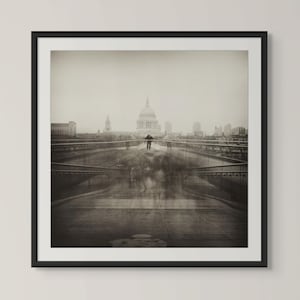 Puede incluir: Impresión enmarcada en blanco y negro de un paisaje urbano con un puente con figuras borrosas y un edificio con cúpula prominente al fondo. La imagen tiene una estética vintage, en tonos sepia.