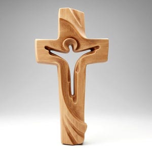 Puede incluir: Una cruz de madera con un diseño tallado. La cruz presenta una figura en su centro, con líneas fluidas y un acabado de veta de madera natural. El diseño es un símbolo de fe y espiritualidad.