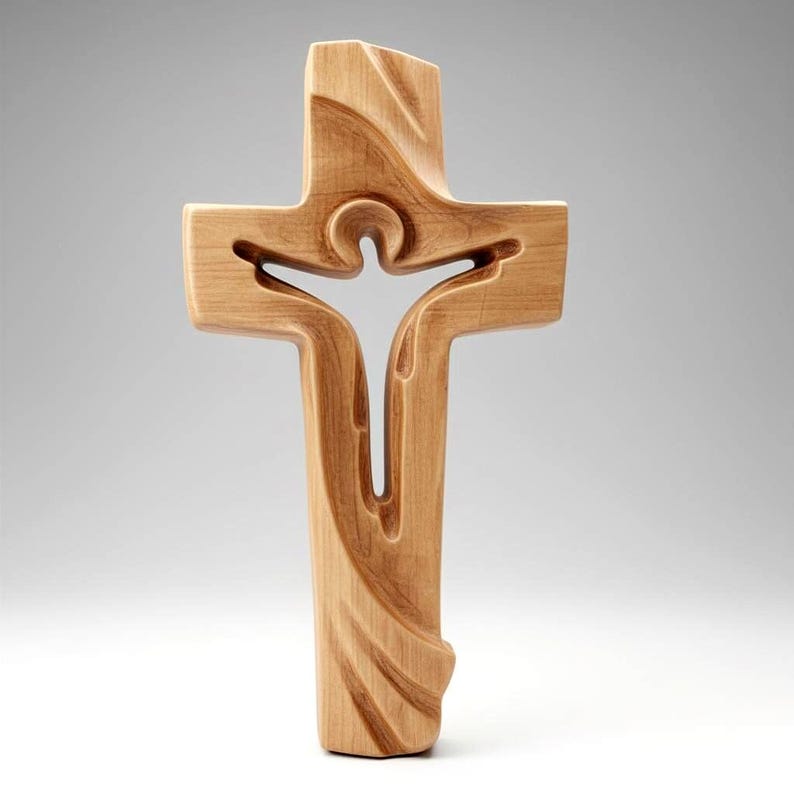 May include: A wooden cross with a carved design. The cross features a figure within its center, with flowing lines and a natural wood grain finish. The design is a symbol of faith and spirituality.