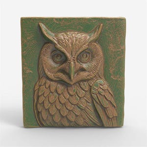 May include: A square, ceramic owl relief sculpture. The owl is depicted in shades of brown and green, with detailed feathering and large, focused eyes. The background is a textured green.