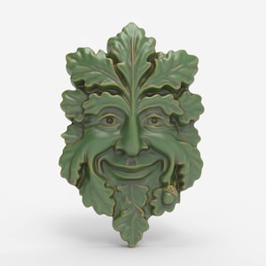 May include: A green ceramic Green Man face sculpture with a smiling expression. The face is surrounded by detailed leaves and an acorn. The sculpture is a decorative item, suitable for indoor or outdoor display.