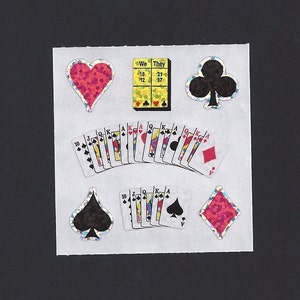 May include: A set of colorful, glittery stickers featuring playing cards, hearts, clubs, and a game board with the words "We" and "They" on it.