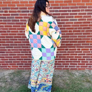 May include: A quilted jacket featuring a patchwork design of yellow, blue, green, and purple floral squares, paired with wide-leg trousers showcasing a multi-colored botanical and paisley print in shades of blue, red, yellow, and green.