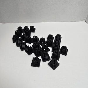 May include: A white ceramic mug with a black handle and the text "But First, Coffee" in a bold, black font. The mug is set against a blurred background, suggesting a cozy setting.