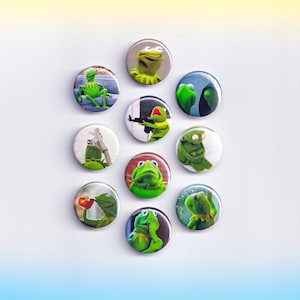 May include: A collection of eleven round buttons featuring various images of Kermit the Frog. The buttons showcase Kermit in different poses and expressions, with a variety of backgrounds. The buttons are primarily green, with white and other colors.
