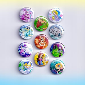 May include: A collection of twelve round, colorful pinback buttons. Each button features a different cartoon illustration of a fairy or fantasy character. The buttons have a glossy finish and are arranged in a grid pattern against a white background.
