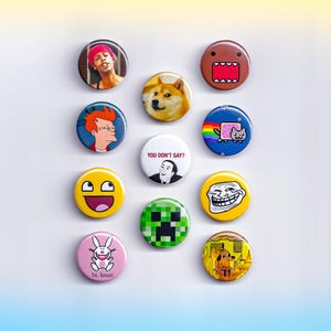 May include: A collection of round, colorful pinback buttons featuring various pop culture references and memes. Designs include a Shiba Inu dog, Domo, Nyan Cat, and the phrase "You Don't Say?"