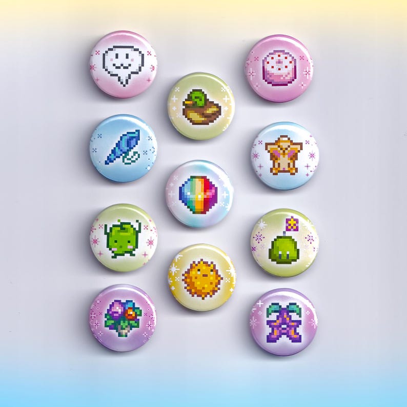 May include: Twelve round buttons with pixelated designs. Each button displays a different colourful graphic, such as a speech bubble, bird, duck, cake, and other whimsical images. The buttons are arranged on a white surface.