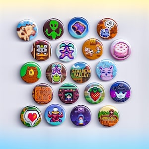 May include: A collection of colorful, pixelated button pins featuring various designs. The pins showcase images of animals, characters, and text, including "Stardew Valley" and "The Stardrop Saloon". The pins are round and have a glossy finish.