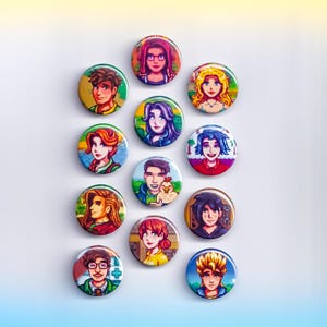 May include: A collection of twelve round pinback buttons featuring pixelated portraits of characters from a video game. The buttons display various characters with different hairstyles, skin tones, and clothing. The buttons are arranged on a white surface.